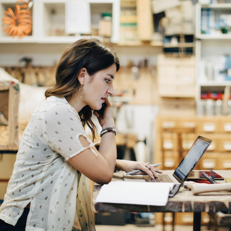 Young woman standing at a laptop in a warehouse